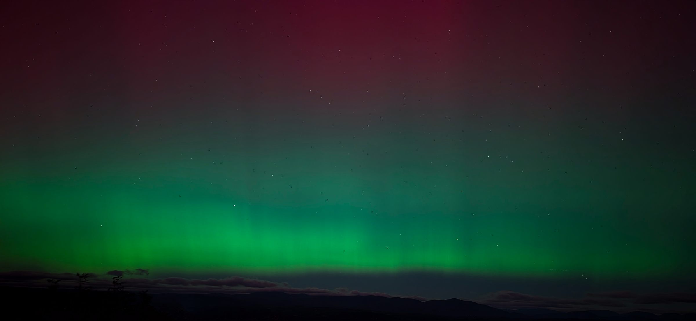 The aurora glowing green over an Appalachian ridge line at night